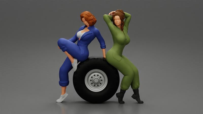 Two sexy girls in mechanic suits are sitting on a truck tire